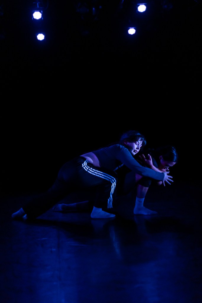 dancer tenderly embracing a crounched dancer