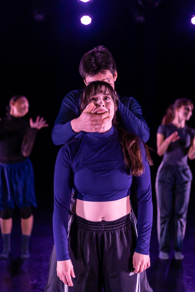 dancer with worried expression as abother dancer holder her face from behind